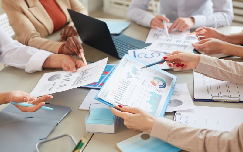 High angle closeup of unrecognizable businesswoman holding data chart with statistics info while planning finance plan during meeting in office, copy space