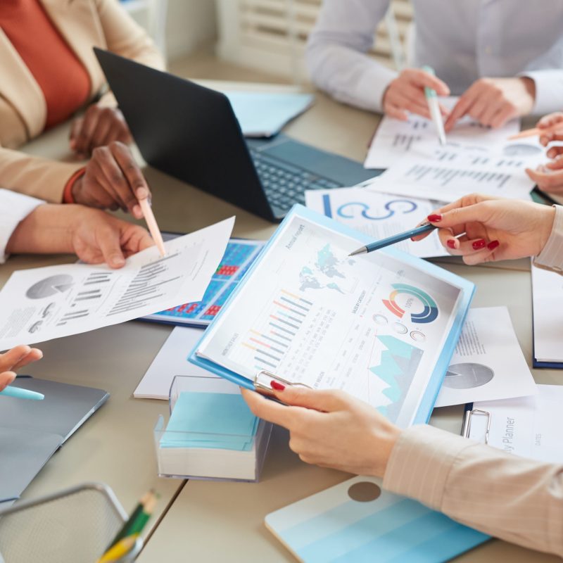 High angle closeup of unrecognizable businesswoman holding data chart with statistics info while planning finance plan during meeting in office, copy space