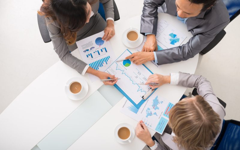 Business executives discussing charts and diagrams at meeting, view from above